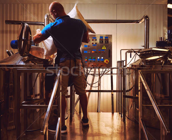 Brewer in brewhouse pouring out the malt to the tank Stock photo © amok