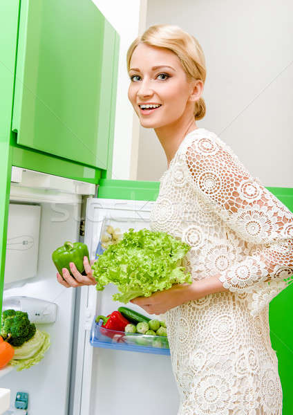 Smiling young woman taking vegetables out of fridge Stock photo © amok
