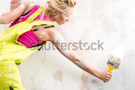 Female worker in coverall paint a  wall and showing thumbs up Stock photo © amok
