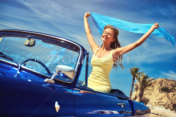 Stock photo: Happy woman with a hands raised sitting in retro cabriolet car