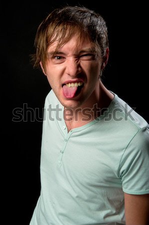 Handsome young man making funny face sticking out tongue Stock photo © amok
