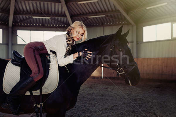 Beautiful elegant young blonde girl lies on a her black horse dressing uniform competition white blo Stock photo © andreonegin
