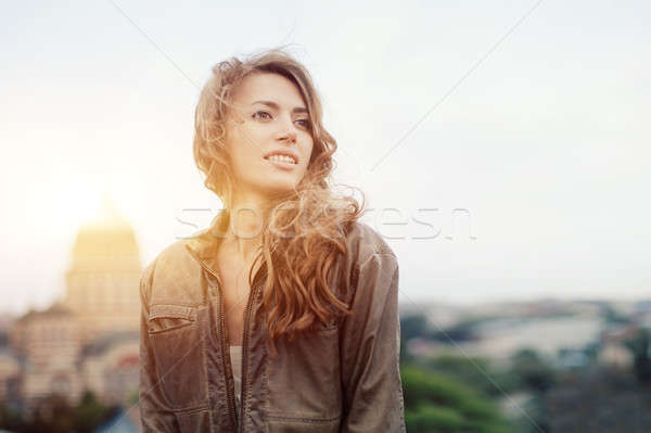 Young attractive woman with good mood enjoying beautiful city landscape while standing on a roof of  Stock photo © andreonegin