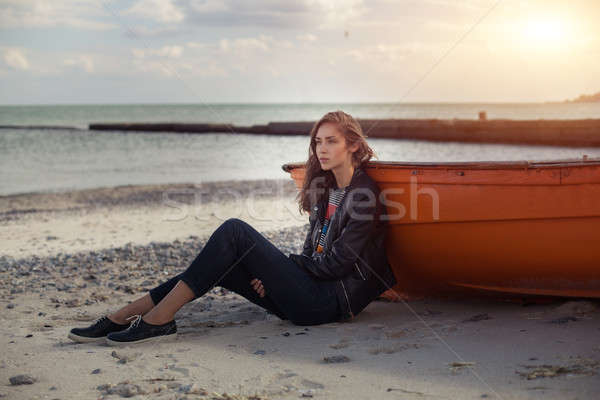 A girl sideways near a red boat on the beach by the sea Stock photo © andreonegin