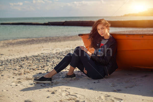 Stock photo: A girl sideways near a red boat on the beach by the sea