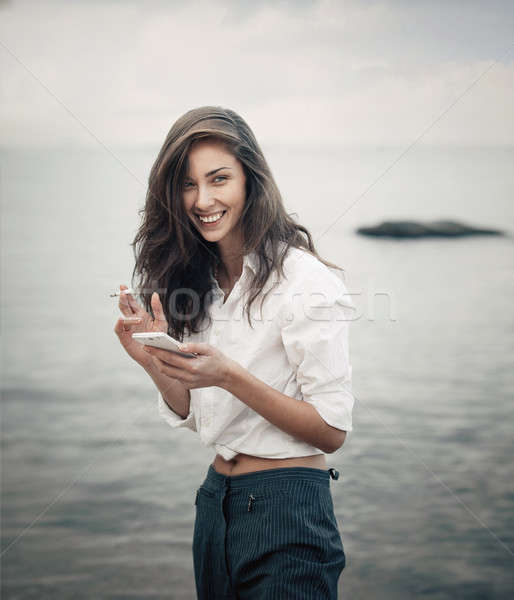 Portrait of teenager girl walking on the beach is checking online the mobile phone waiting for a mes Stock photo © andreonegin