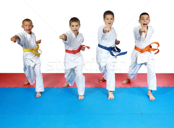 Four sportsman in karategi and with belts are beating blows hands Stock photo © Andreyfire