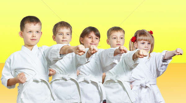 Stock photo: Five little athletes hits a punch arm on a yellow background