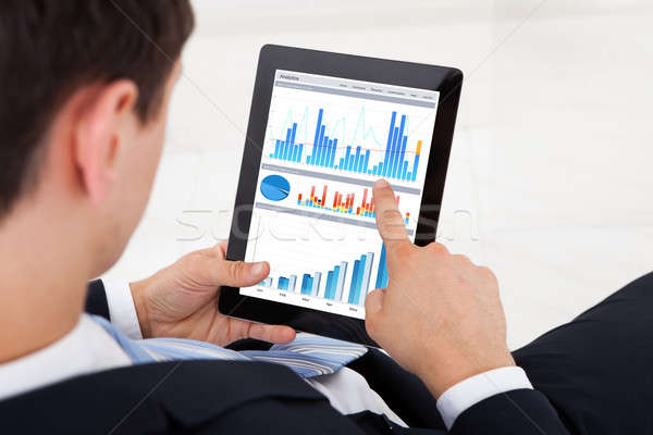 Businessman Comparing Graphs On Digital Tablet In Office Stock photo © AndreyPopov