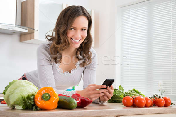Gülümseyen cep telefonu genç kadın sebze gülen mutfak Stok fotoğraf © AndreyPopov