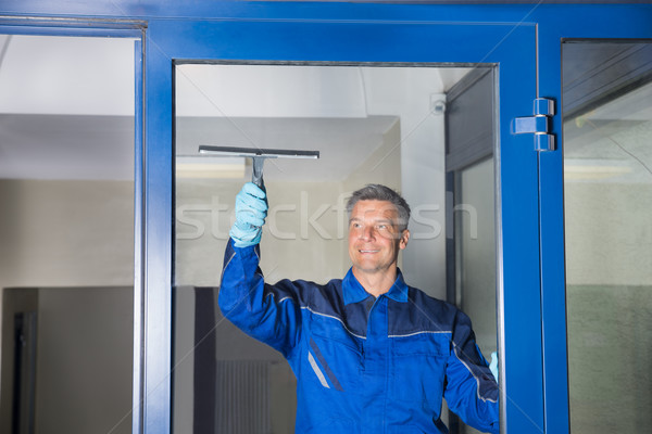 Male Worker Cleaning Glass With Squeegee Stock photo © AndreyPopov