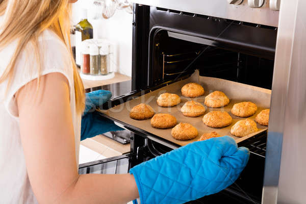 Woman Placing Tray Full Of Cookies In Oven Stock photo © AndreyPopov
