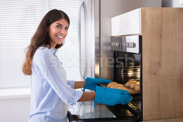 Woman Taking Out Tray Of Baked Bread From Oven Stock photo © AndreyPopov