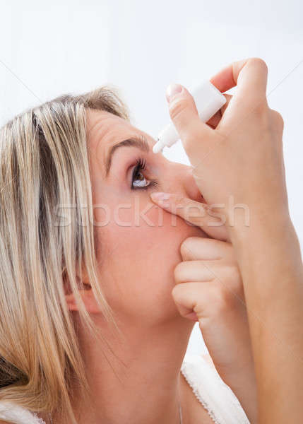 Woman pouring drops in her eyes Stock photo © AndreyPopov