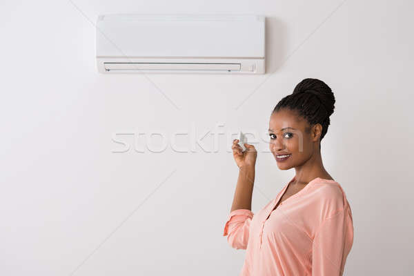 Woman Operating Air Conditioner With Remote Control Stock photo © AndreyPopov