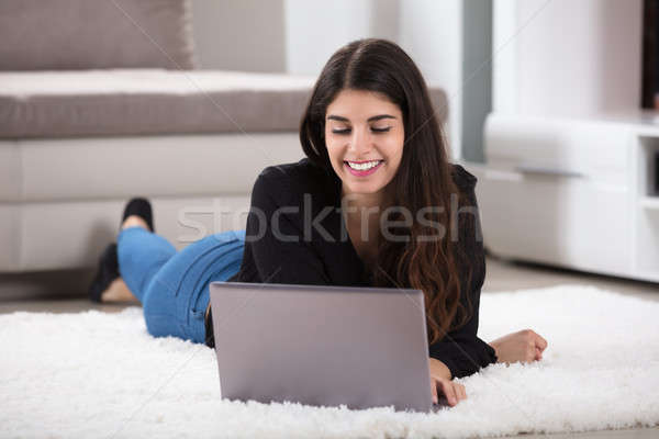 Young Woman Lying On Rug Using Laptop Stock photo © AndreyPopov