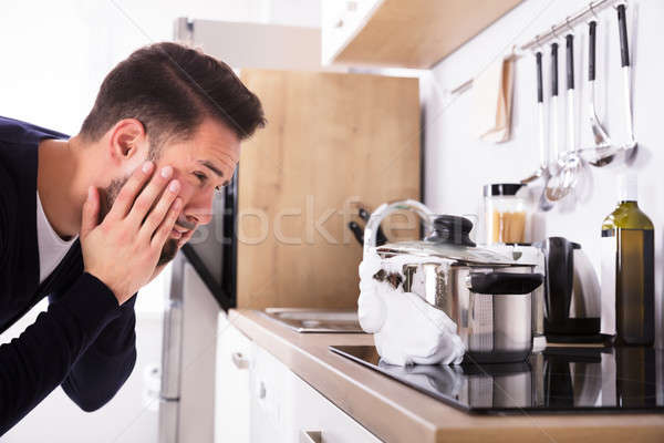 Man Looking At Spilling Out Boiled Milk From Utensil Stock photo © AndreyPopov