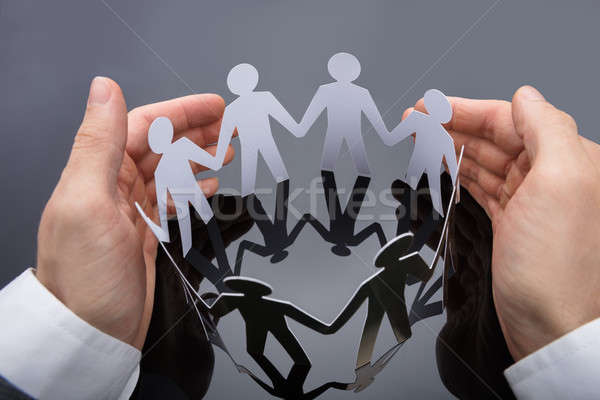 Businessperson's Hand Protecting Cut-out Figures Stock photo © AndreyPopov