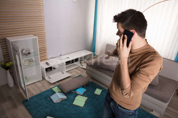 Stock photo: Man Talking On Phone And Pointing At Stolen Television