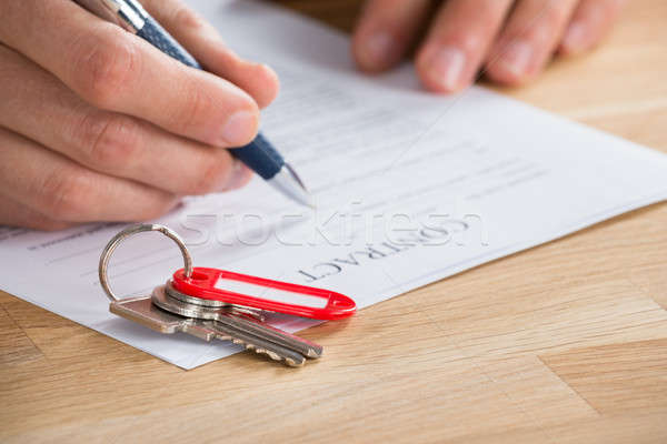 Businessman Signing Contract With Keys On It Stock photo © AndreyPopov