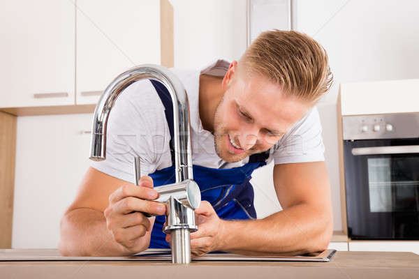 Plumber Fixing Faucet In Kitchen Stock photo © AndreyPopov