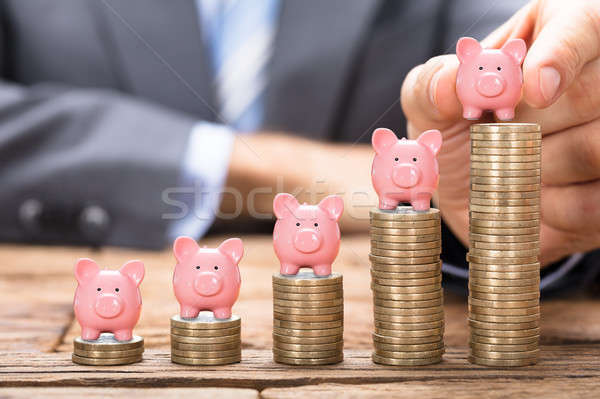 Businessman Placing Piggybank On Stacked Coins Stock photo © AndreyPopov