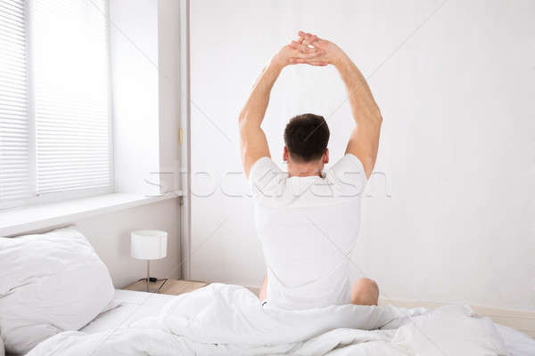 Man Stretch His Hand After Wake Up In Bed Stock photo © AndreyPopov
