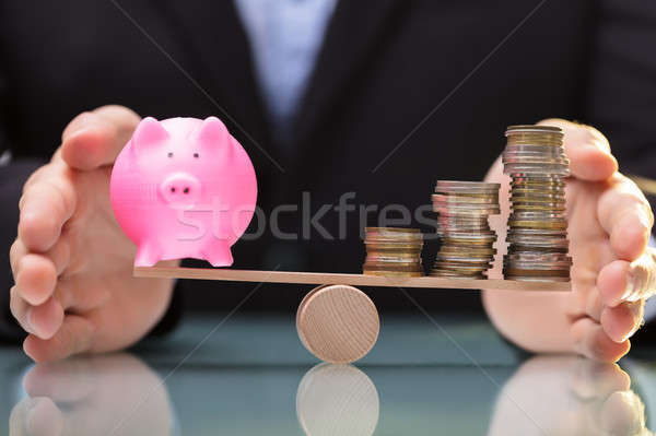 Businessperson Protecting Piggy Bank And Stacked Coins On Seesaw Stock photo © AndreyPopov