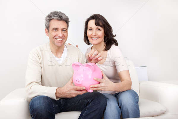 Mature couple saving money in piggybank Stock photo © AndreyPopov