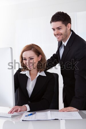 Zakenman naar vrouwelijke collega glimlachend bureau Stockfoto © AndreyPopov