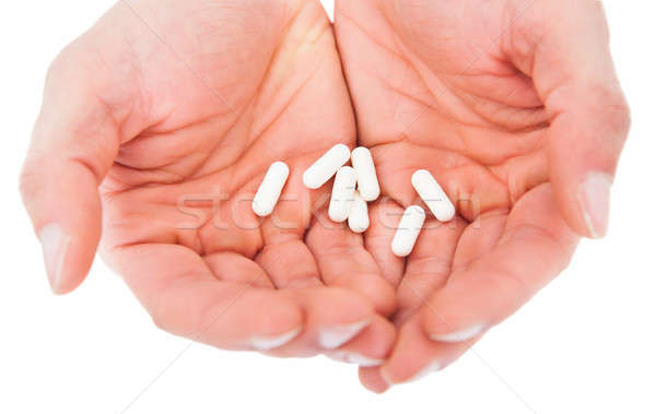 Person's Hand Holding Pills Over White Background Stock photo © AndreyPopov