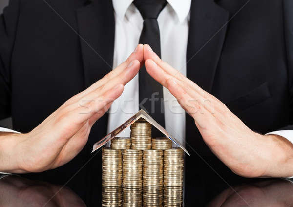 Stock photo: Businessman Shielding House Made Of Money At Desk