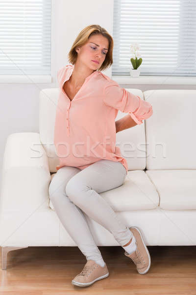 ストックフォト: 女性 · ソファ · 腰痛 · 若い女性 · 座って