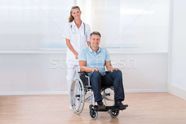 Stock photo: Doctor Carrying Patient On Wheelchair