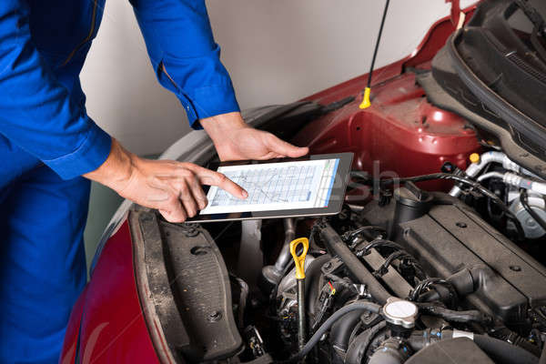 Stock photo: Mechanic Using Digital Tablet While Examining Car Engine