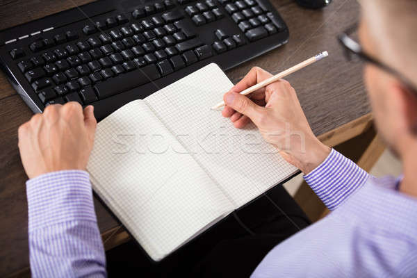 Stock photo: Businessman Writing Down In Checkered Notebook