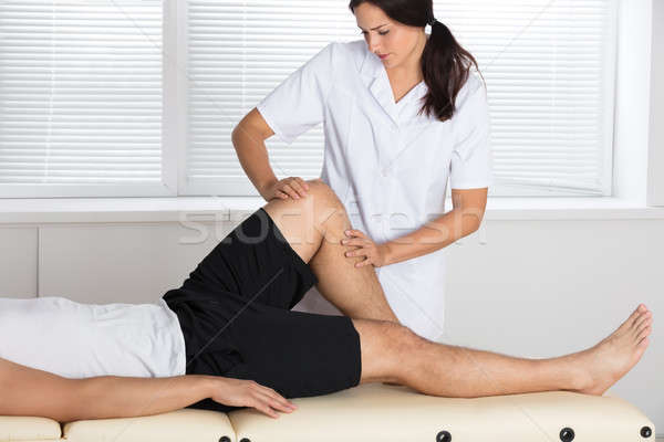 Physiotherapist Giving Leg Exercise In Clinic Stock photo © AndreyPopov