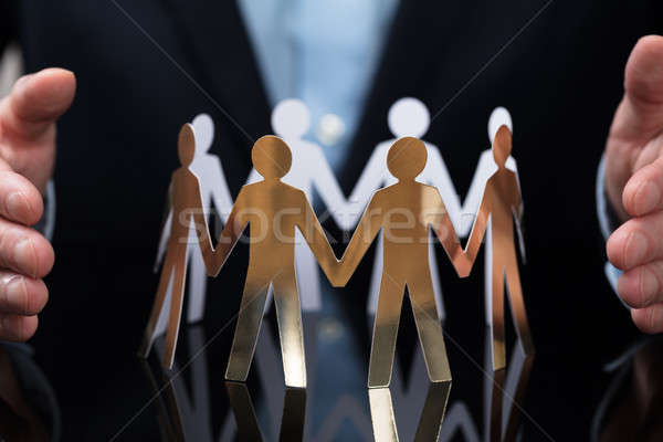 Businessperson Protecting Paper Cut Out People Stock photo © AndreyPopov