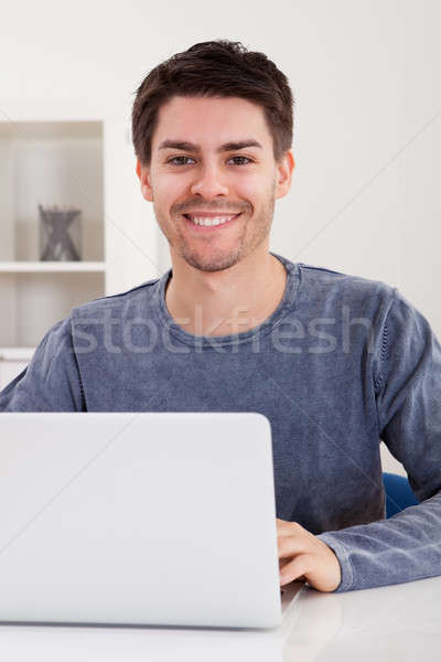 Smiling young man using a laptop Stock photo © AndreyPopov