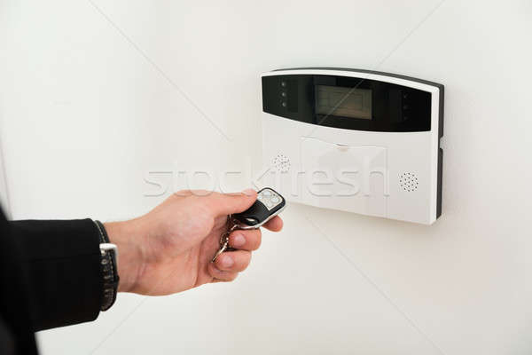 Hands With Remote Control In Front Of Security System Stock photo © AndreyPopov