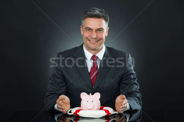 Stock photo: Mature Businessman Protecting Piggybank With Lifebelt