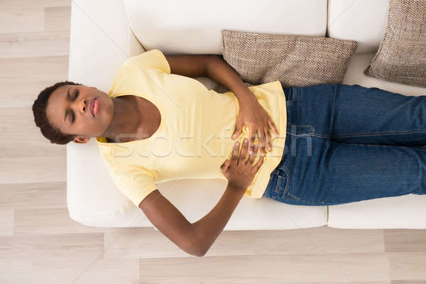 Mujer sufrimiento dolor de estómago jóvenes África sofá Foto stock © AndreyPopov