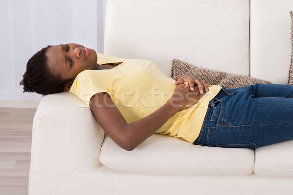 Mujer sufrimiento dolor de estómago jóvenes África sofá Foto stock © AndreyPopov