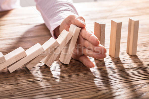 Business Woman's Hand Stopping Falling Blocks On Table Stock photo © AndreyPopov