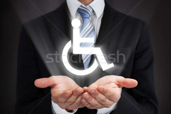 Businessman holding glowing disability sign Stock photo © AndreyPopov