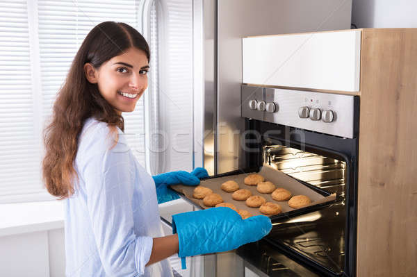 Woman Taking Out Tray Of Baked Cookies From Oven Stock photo © AndreyPopov