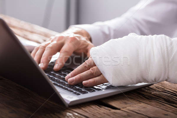 Businessperson With Hand Injury Using Laptop Stock photo © AndreyPopov