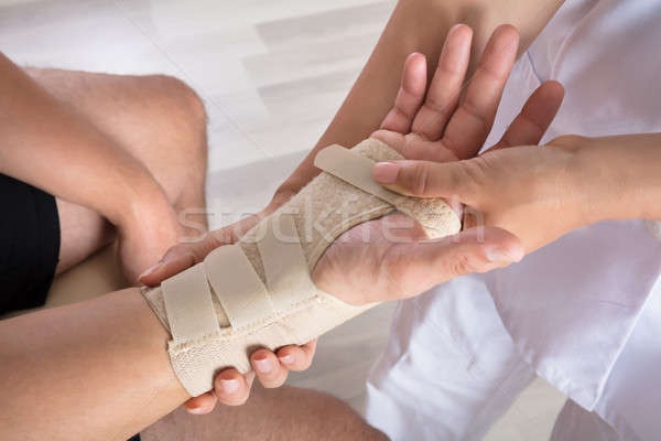 Orthopedist Fixing Plaster On Injured Person's Hand Stock photo © AndreyPopov