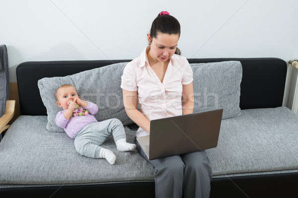 Vrouw met behulp van laptop vergadering sofa baby spelen Stockfoto © AndreyPopov