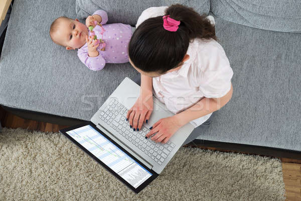 Vrouw met behulp van laptop vergadering sofa baby spelen Stockfoto © AndreyPopov